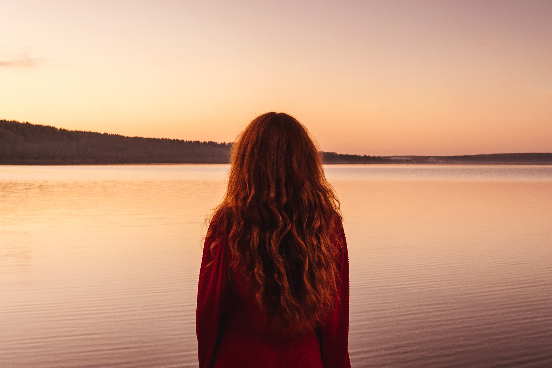 Red haired woman at sunset, back view.